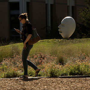 A women glancing at her phone as she passes one of the many campus eggheads