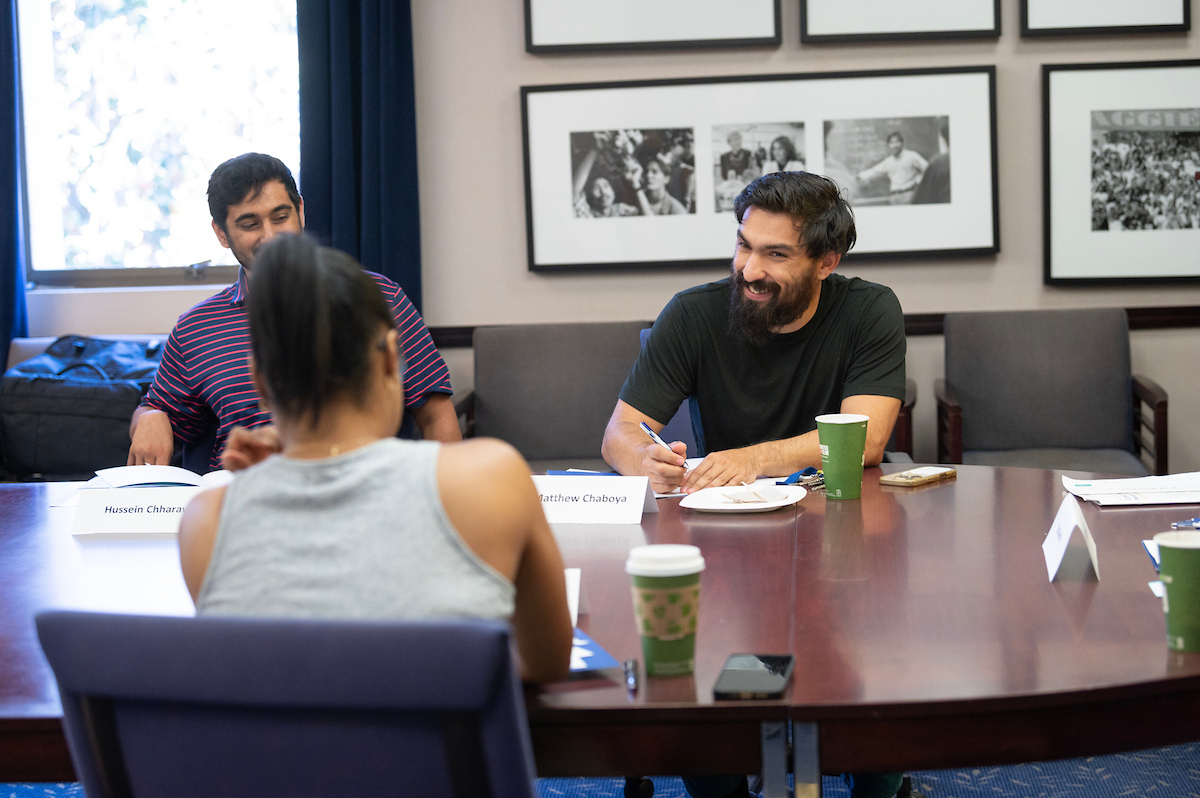 Four young adults smiling around a conference table with papers and coffee (photo)