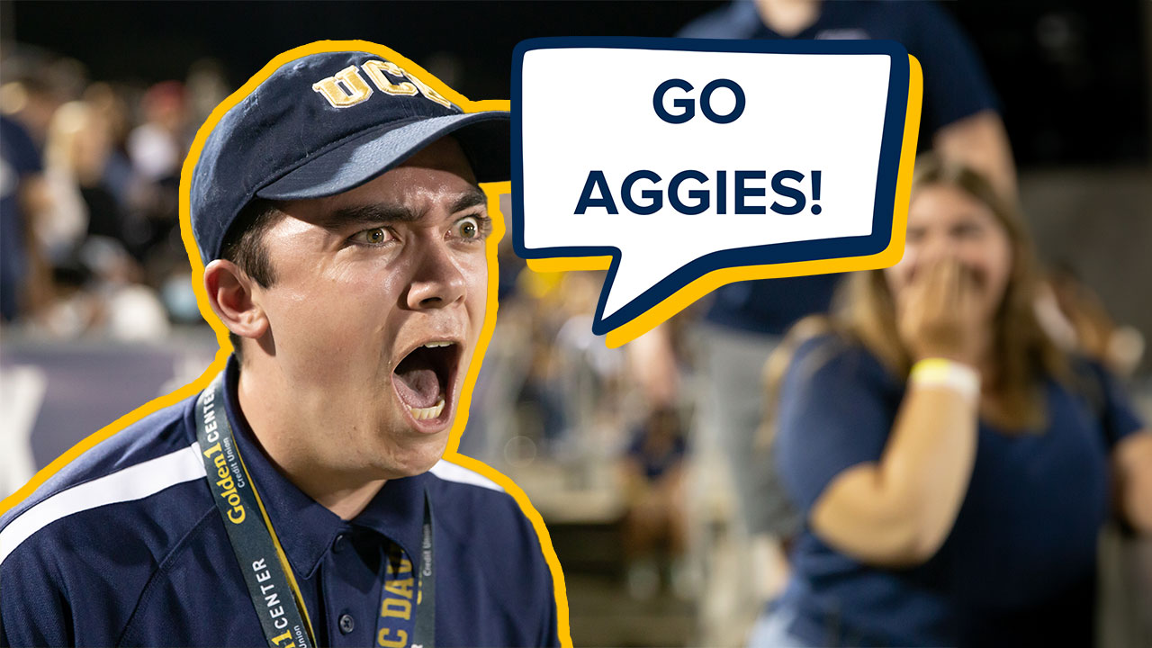 A spirited UC Davis student, clad in university colors and a baseball cap, shouts with fervor, surrounded by the bustling energy of fellow fans at the Homecoming football game. A speech bubble graphic that reads "Go Aggies!" is overlaid atop the photo.