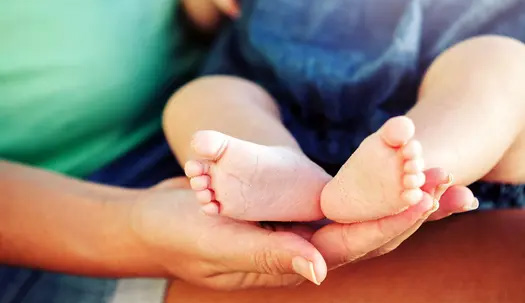 An adult hand holding a baby's feet