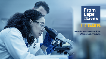 A scientist examines a sample under a microscope in a laboratory setting.