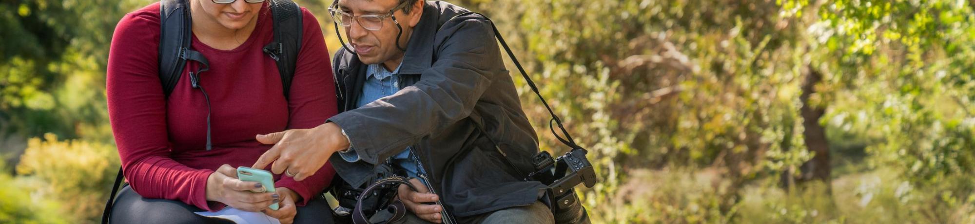 uc davis photographer shows person some photography tips while sitting on a bench outside