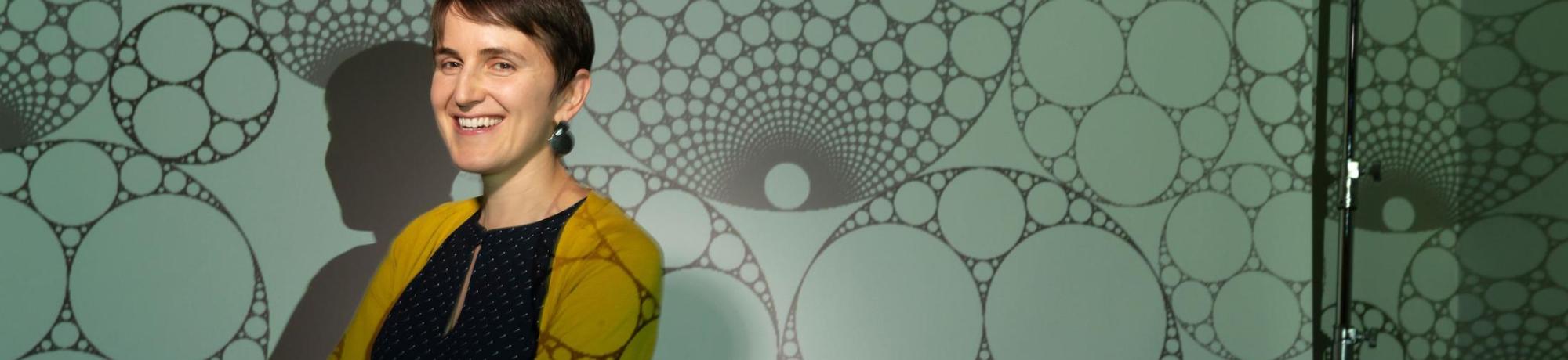A math professor poses for a unique phot featuring a patterned background
