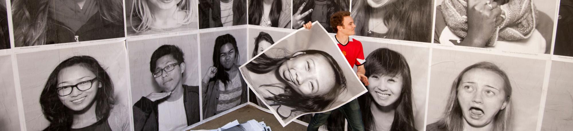 A student pastes portraits of his peers on wall near the social science building