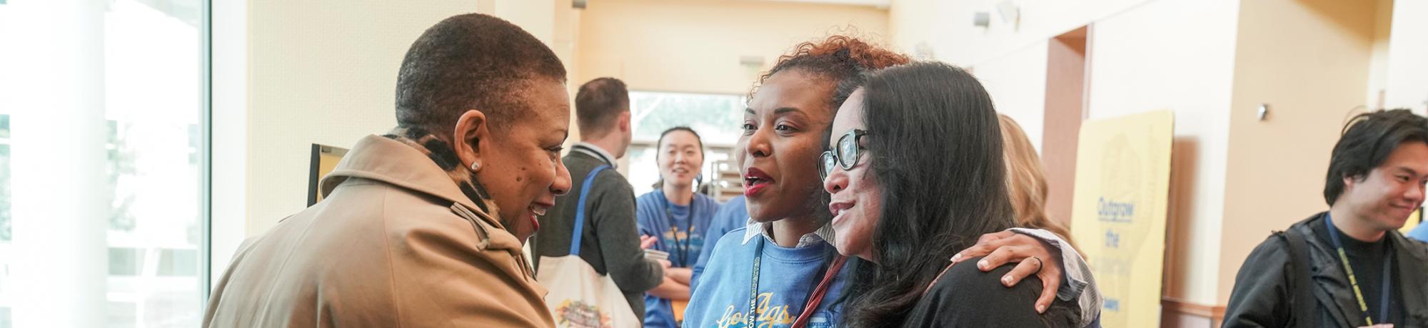 Two women from UC Davis' Office of Strategic Communications shake hands with a guest speaker.